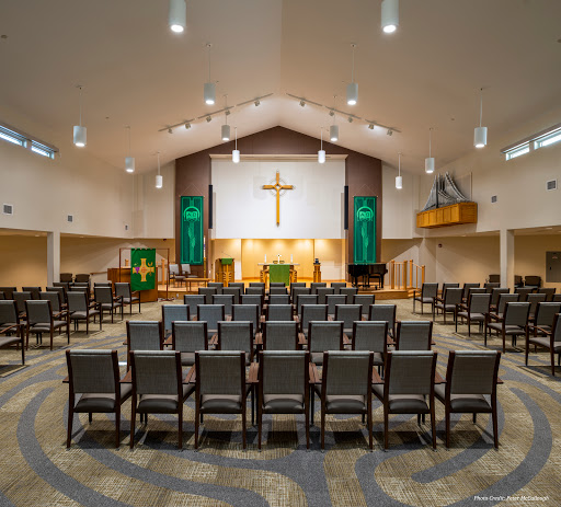 A view of the interior of a modern church sanctuary, featuring rows of chairs and a prominent cross.