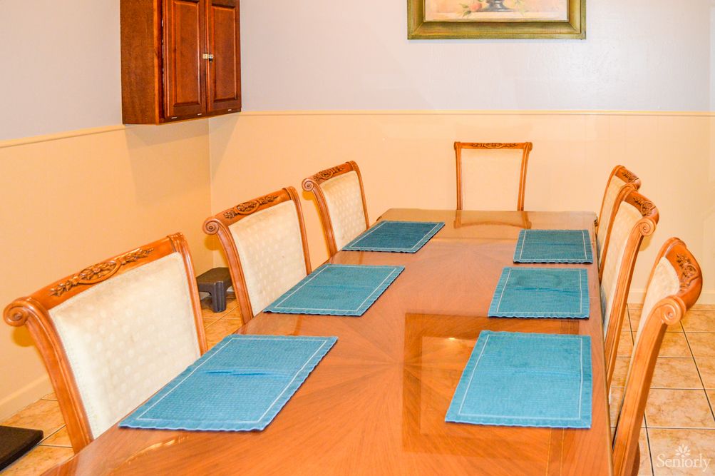 A dining room with a wooden table set for six, featuring blue placemats on each setting.