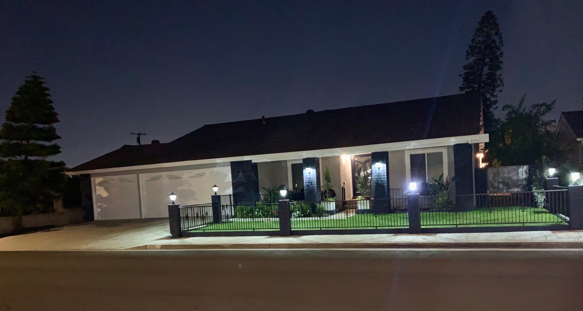 A suburban house illuminated by exterior lights at night.
