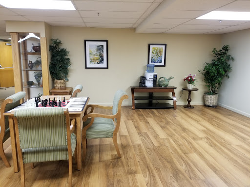 A cozy lounge area featuring a chess table, decorative plants, and framed artwork.