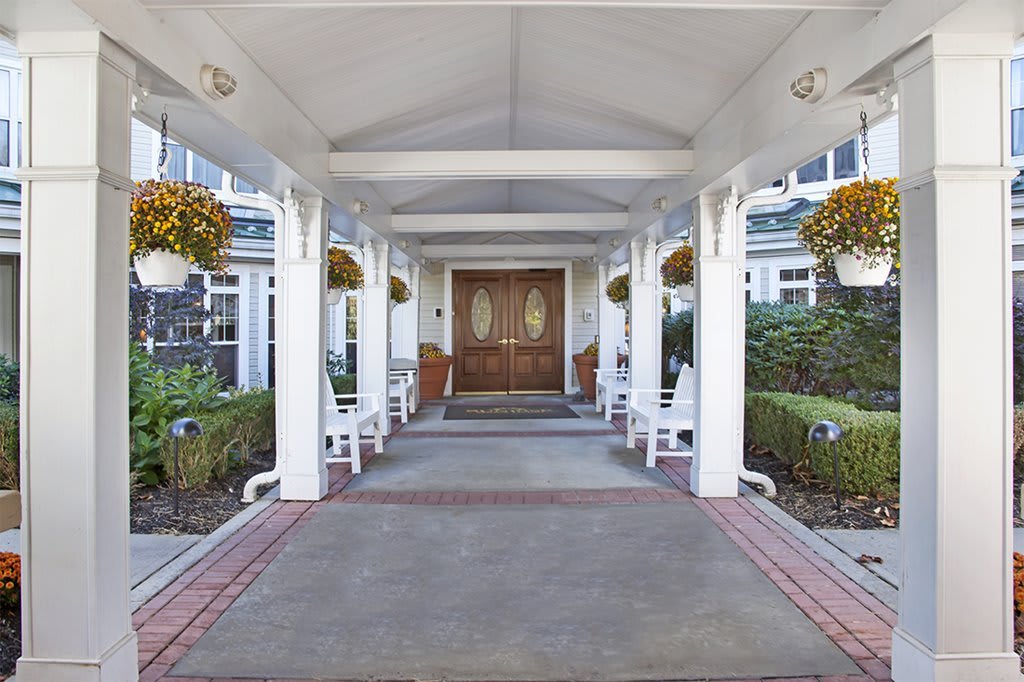 A welcoming entrance with white columns and hanging plants leading to a double door.