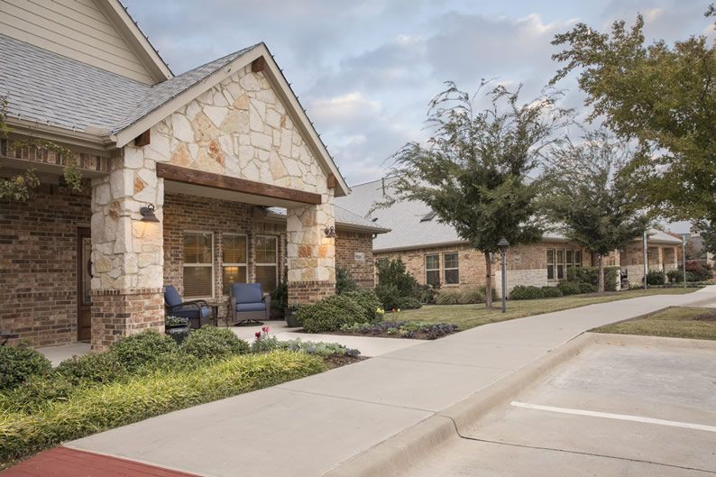 A stone and brick residential building with a manicured landscape and driveway.
