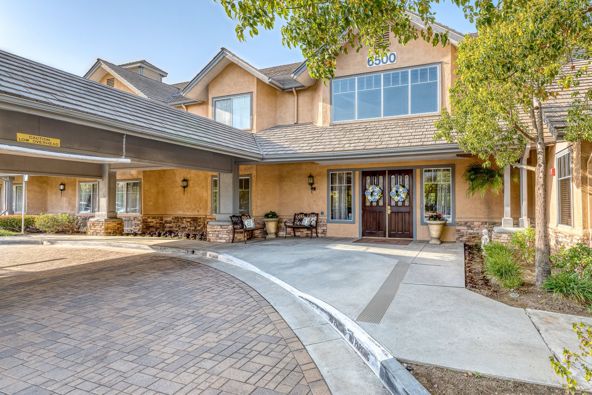 A welcoming residential house with a spacious driveway and porch, surrounded by greenery.