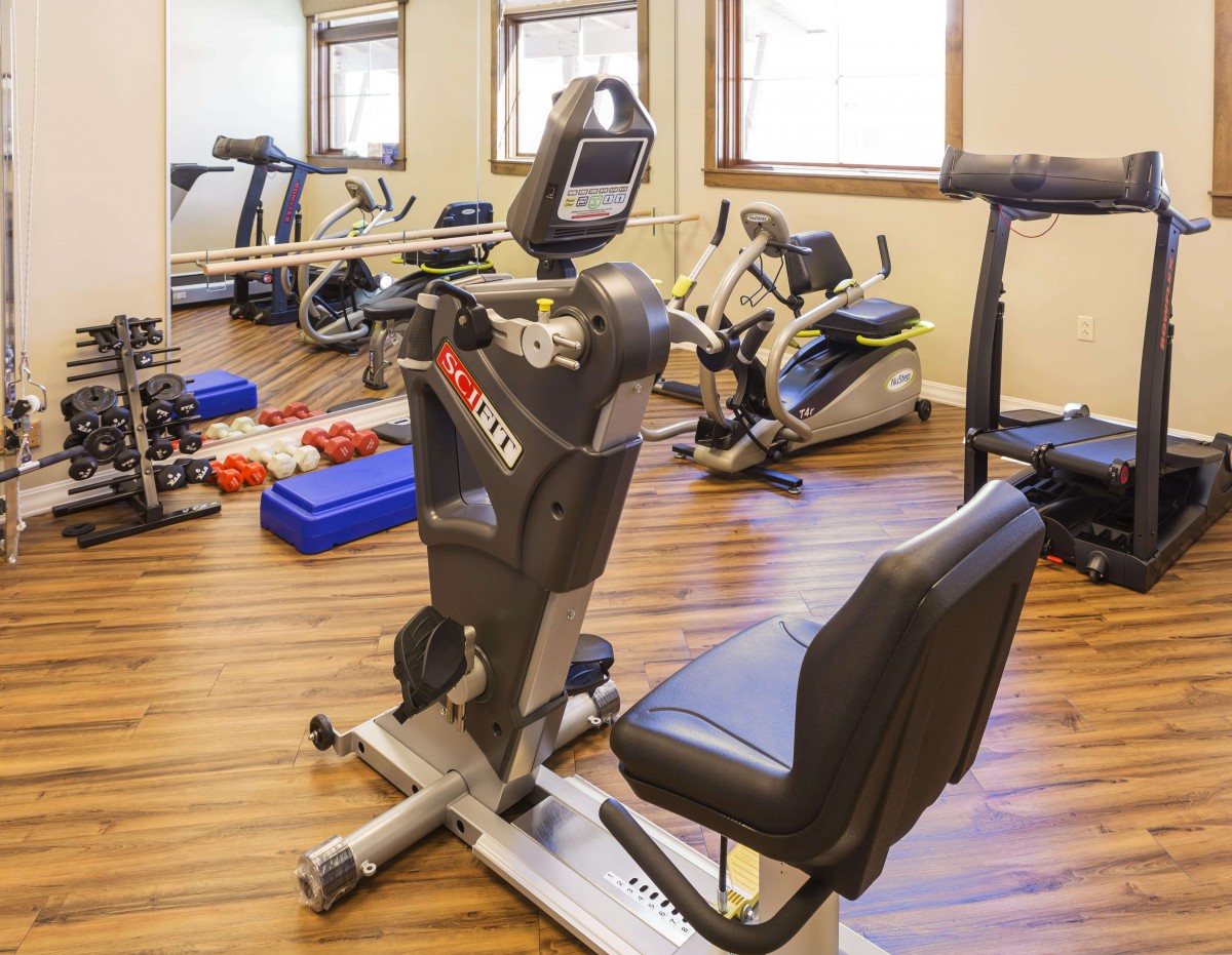 A small indoor gym with various exercise equipment, including a stationary bike, treadmill, and weights.