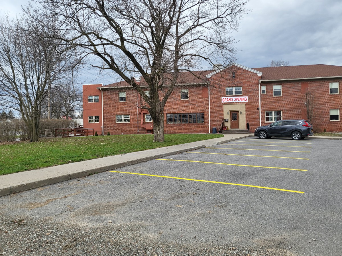 A brick building with an empty parking lot and a tree on a cloudy day.
