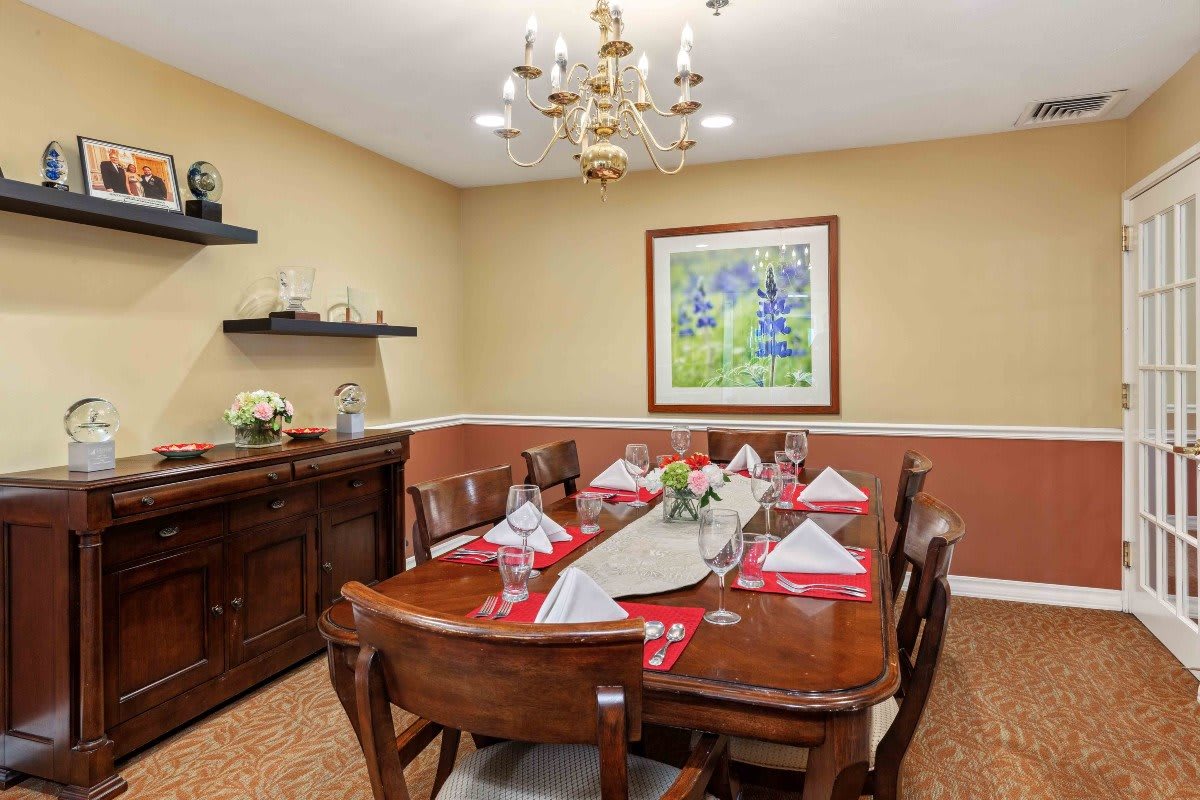 A well-decorated dining room with a neatly set table and elegant chandelier.