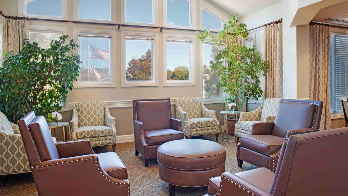 A cozy living room with comfortable armchairs, a coffee table, and large windows allowing natural light to fill the space.