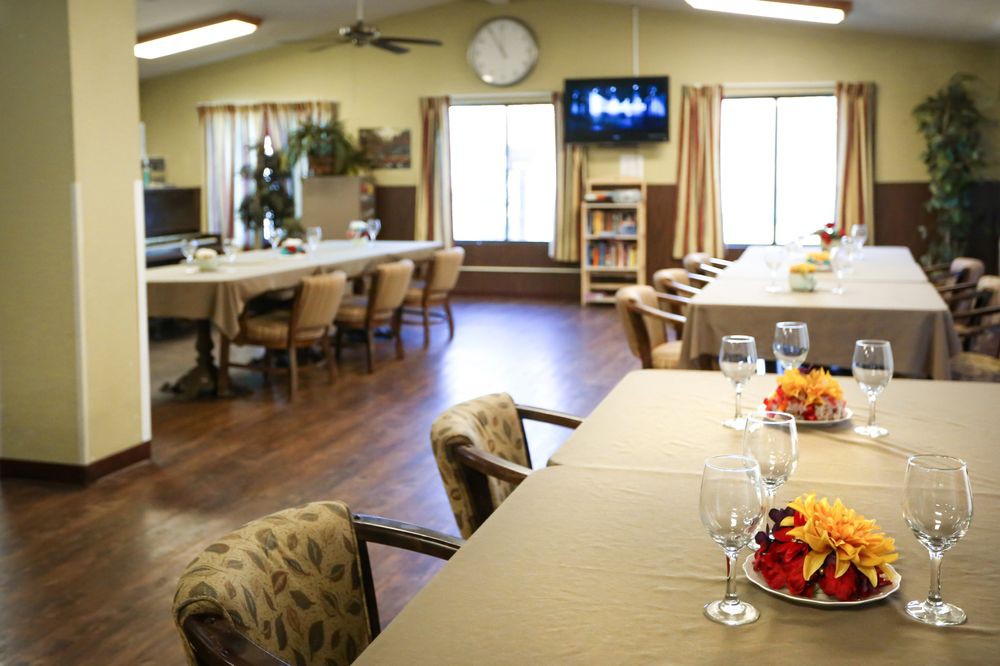 A cozy dining room with set tables and a television on the wall.