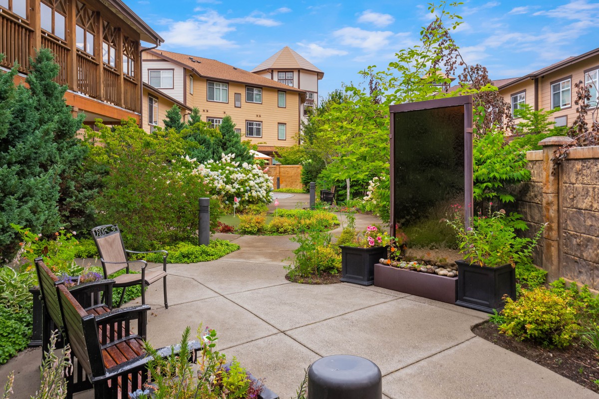 A serene courtyard garden with benches and lush greenery, surrounded by residential buildings.