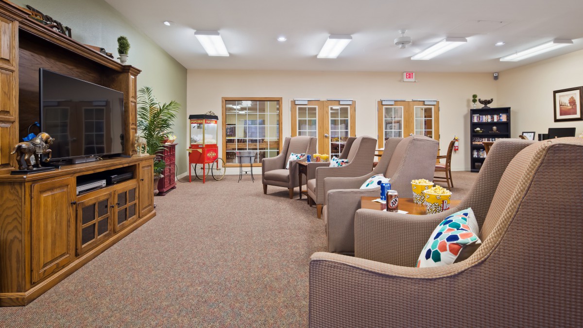 A cozy lounge area featuring comfortable armchairs, a popcorn machine, and an entertainment center.