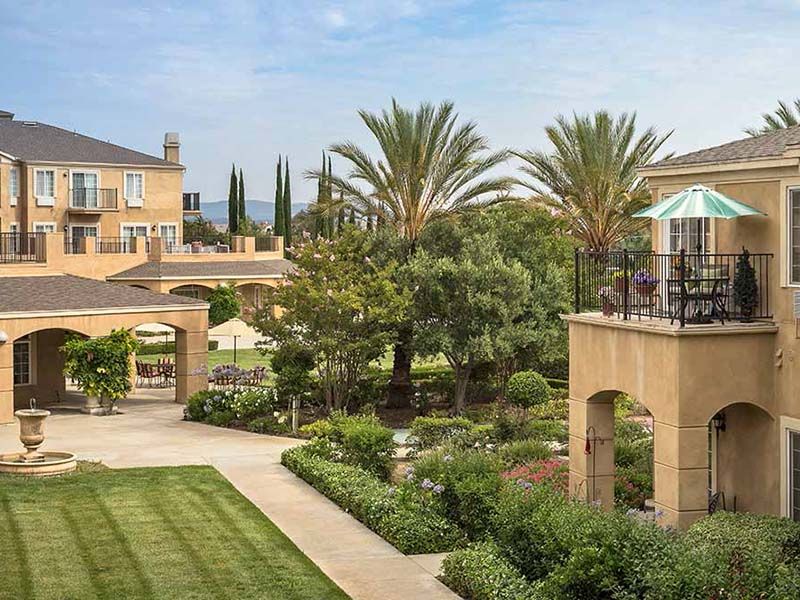 A luxurious resort featuring elegant architecture and beautifully landscaped gardens with palm trees.