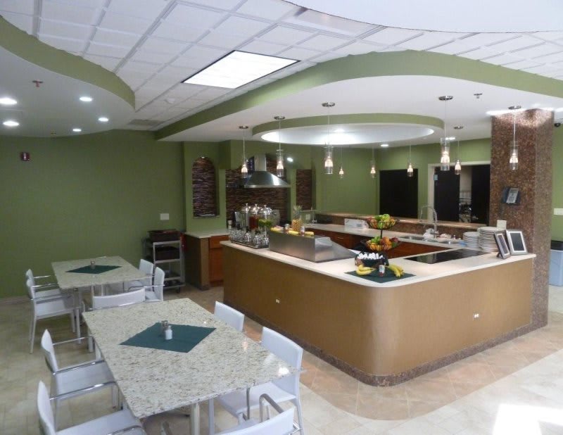 A modern cafeteria interior with dining tables and a serving counter.