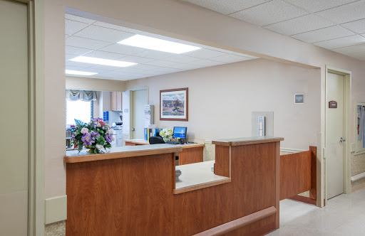A modern reception area in a medical facility, featuring a welcoming desk and floral decorations.
