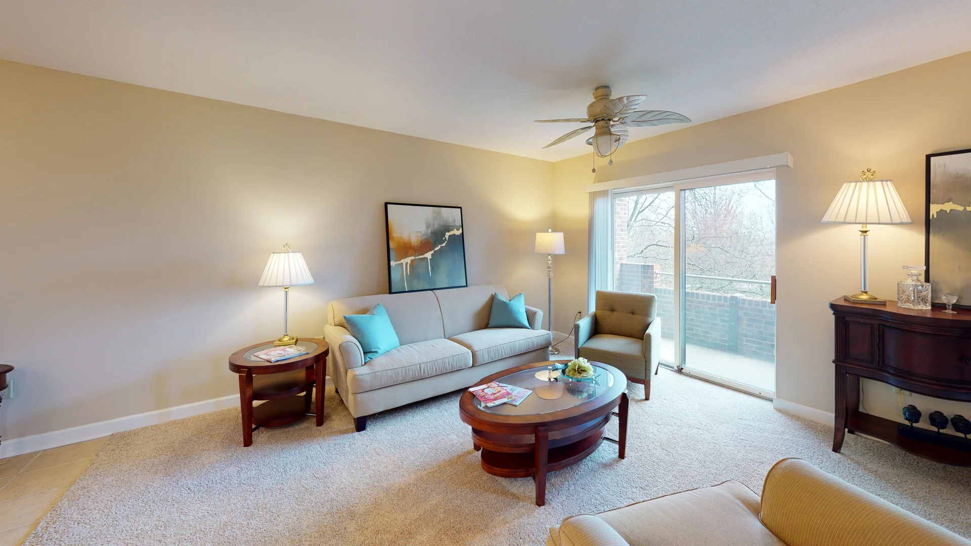 A cozy living room with comfortable seating, coffee table, and a sliding glass door leading to an outdoor balcony.