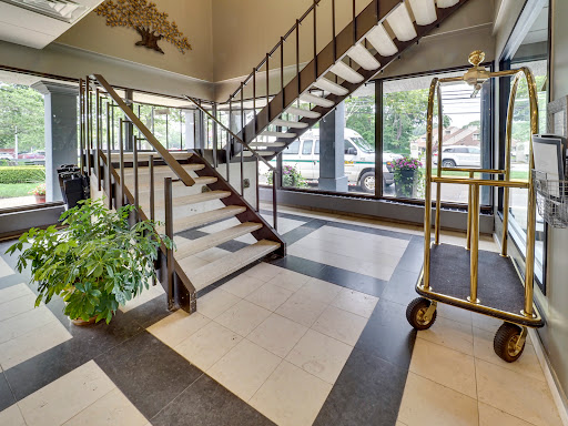 A spacious hotel lobby featuring a modern staircase and large glass windows.