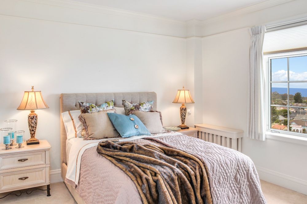 A cozy and elegantly decorated bedroom with a neatly made bed and a warm lamp.