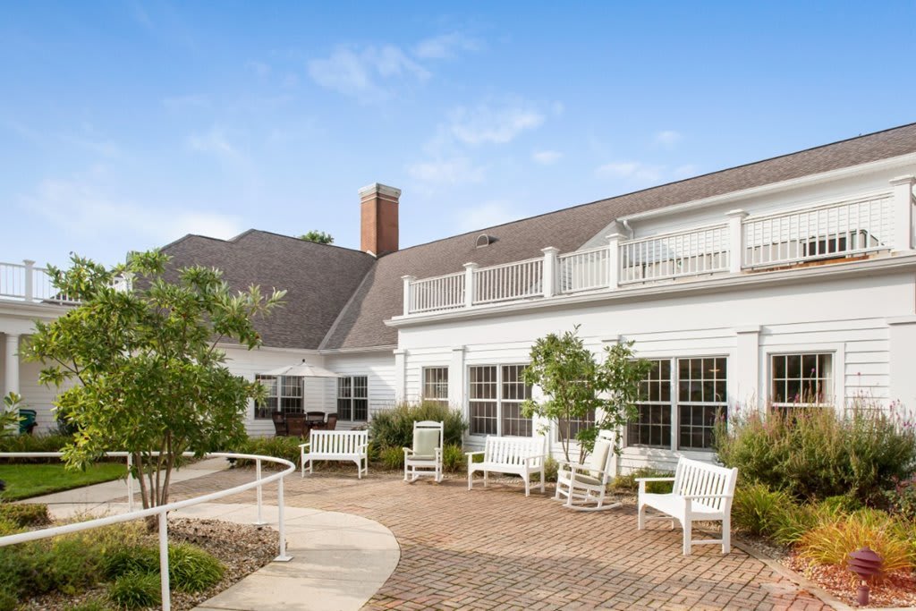 A charming house with outdoor seating and a landscaped garden featuring a brick path.