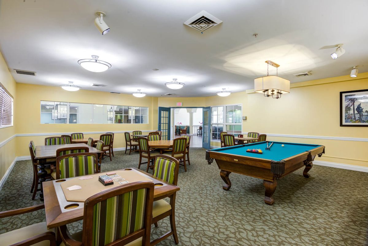 A recreation room featuring a pool table, multiple tables and chairs, and chandeliers on the ceiling.