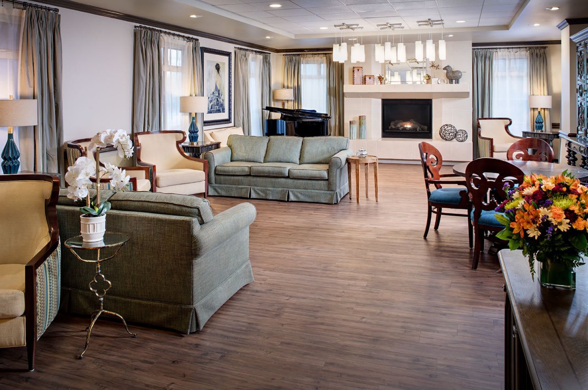A spacious and elegantly decorated living room featuring comfortable seating, a fireplace, and a grand piano.