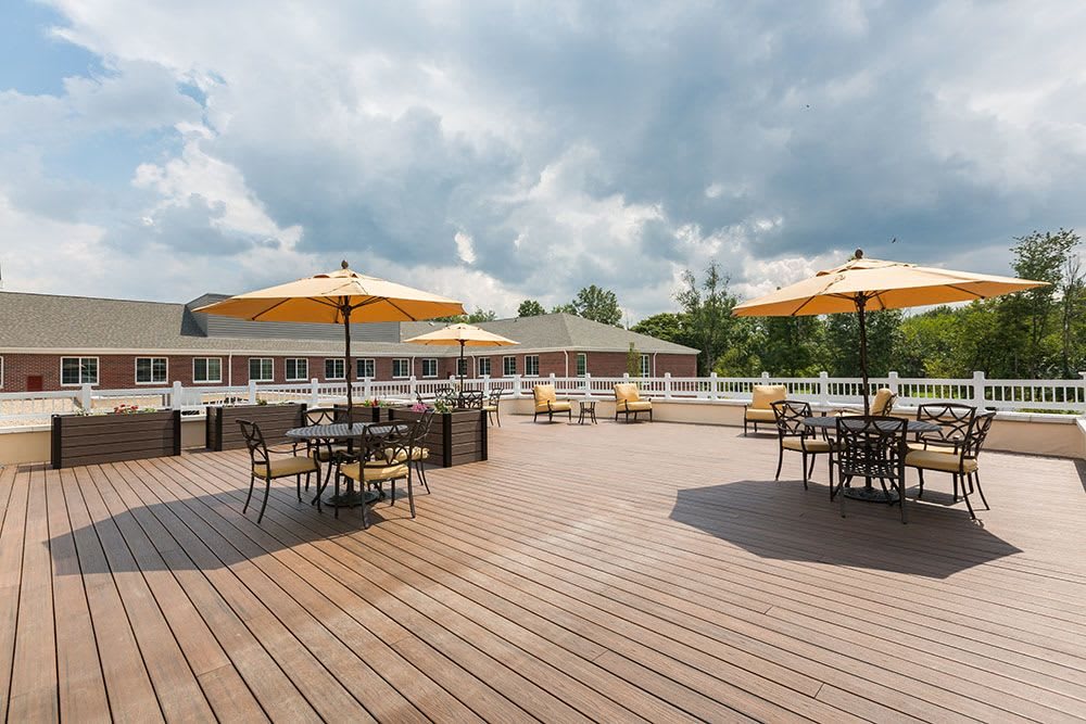 Spacious outdoor patio with tables and umbrellas under a cloudy sky.