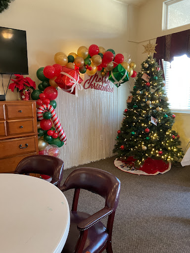 A festive Christmas setup featuring a beautifully decorated tree and colorful balloon arrangements.