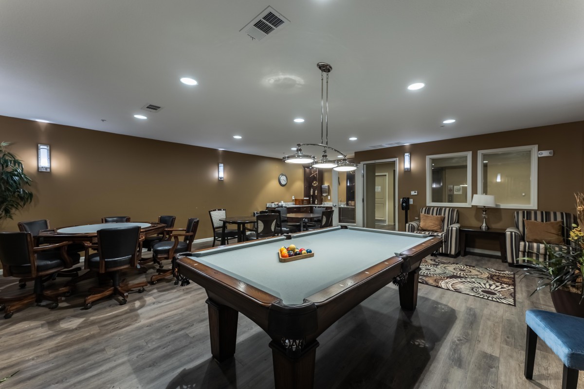 A modern recreation room featuring a pool table and stylish lighting.