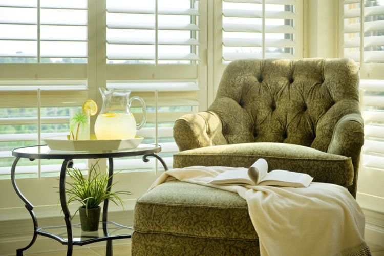 A cozy living room corner with a plush chair, side table, and sunlight streaming through the window.