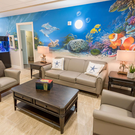 A cozy living room featuring modern furniture and a vibrant underwater-themed mural.