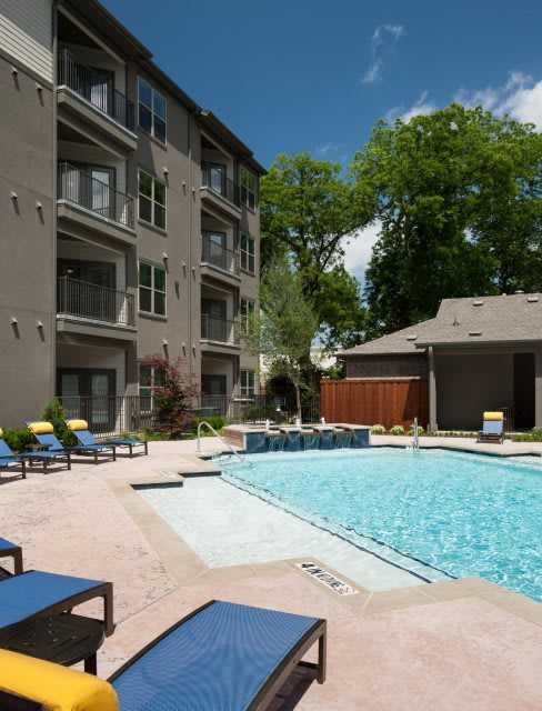 A tranquil apartment complex with a refreshing outdoor pool area on a sunny day.