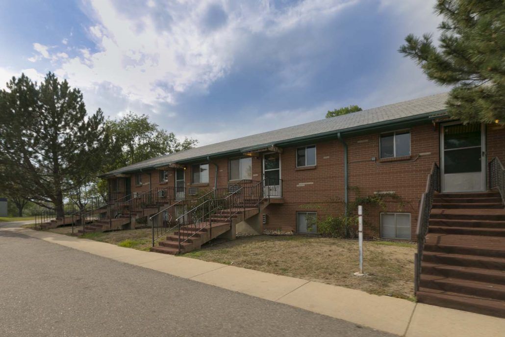 A brick residential building with multiple staircases under a cloudy sky.