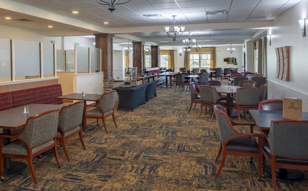 An elegantly designed dining area with tables and chairs, adorned with chandeliers.