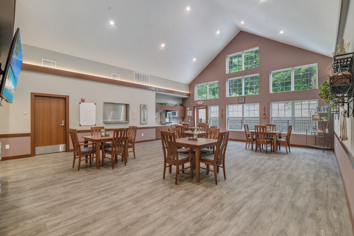 A spacious dining area with large windows and multiple round tables.