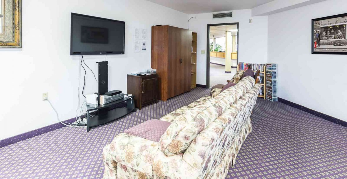 A cozy living room with a floral sofa and a flat-screen TV.