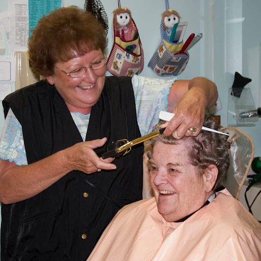 A hairstylist happily cutting the hair of a smiling customer at a salon.
