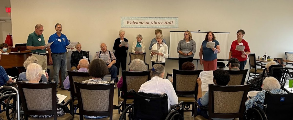 A community meeting with elderly participants presenting in front of an audience.