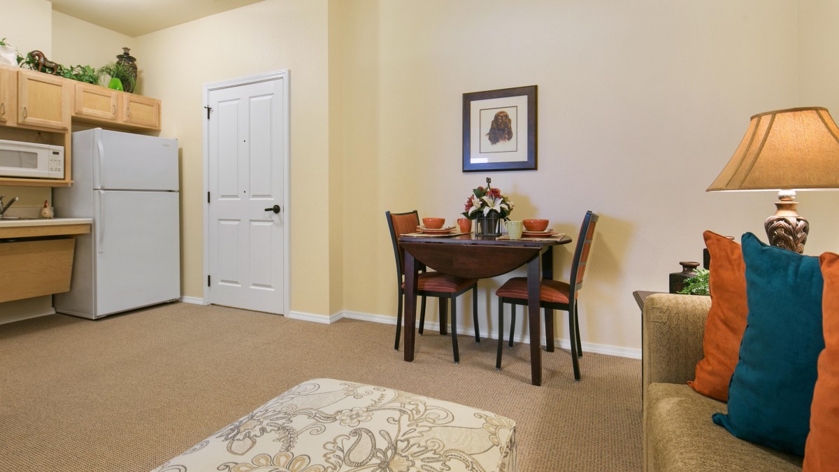 A cozy dining area with a small table set for two, featuring a floral centerpiece and artwork on the wall.