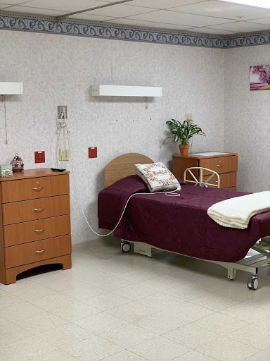 A neatly arranged hospital room featuring a patient bed, essential furniture, and ambient decor.