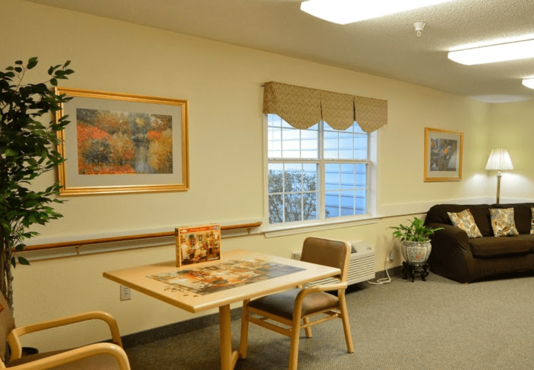 A cozy room with a table and chairs, decorated with wall art and a window view.
