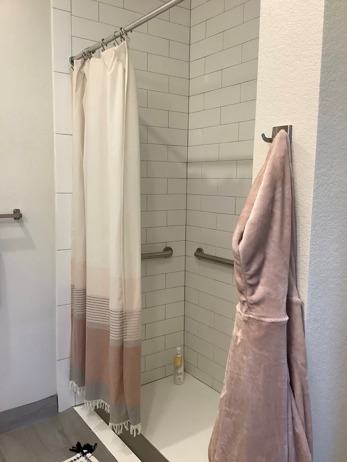 A clean and modern bathroom shower area with a tiled interior and hanging towel.