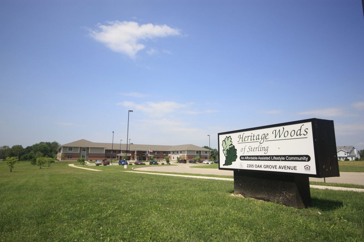 A building with a sign and greenery under a partly cloudy sky.