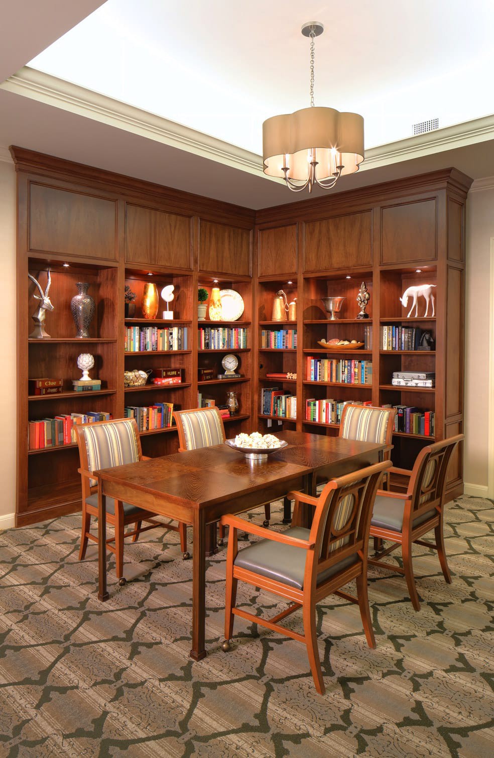 A cozy library corner with wooden bookshelves filled with books and a table set with chairs, perfect for reading and study.
