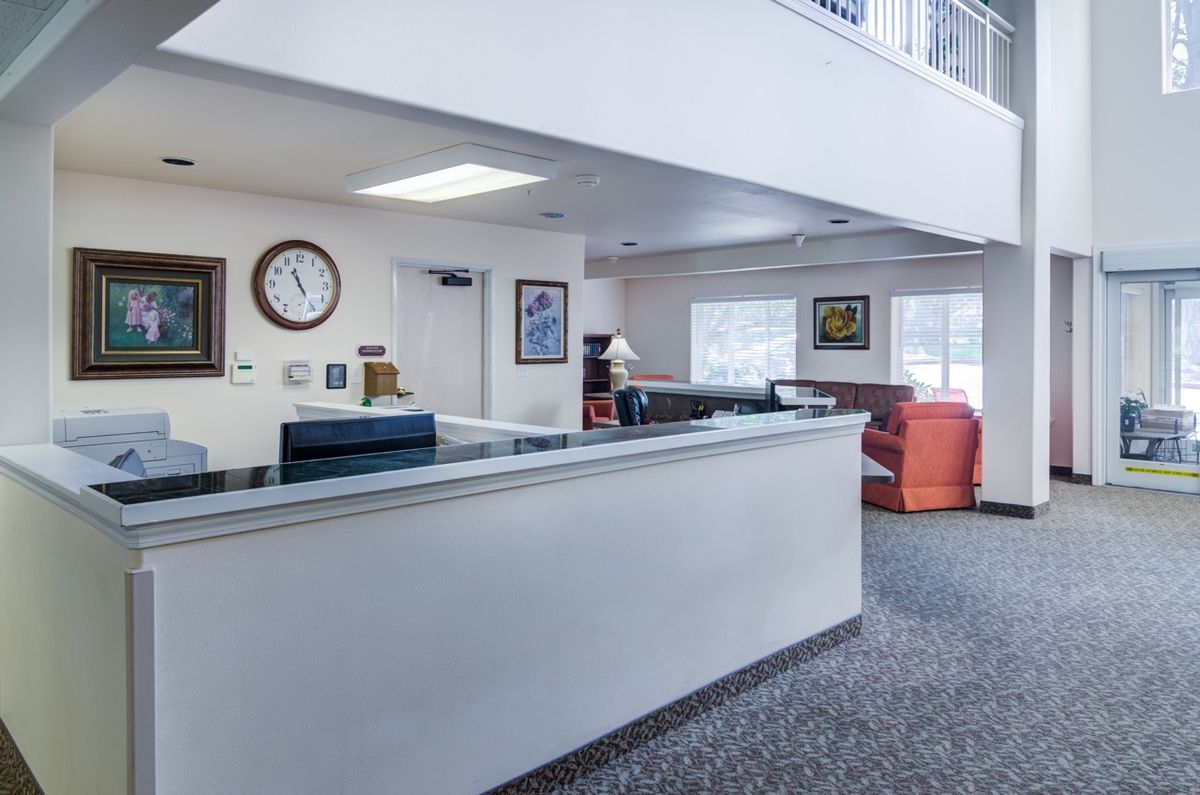 A clean and spacious lobby area featuring a reception desk, seating, and a wall clock.