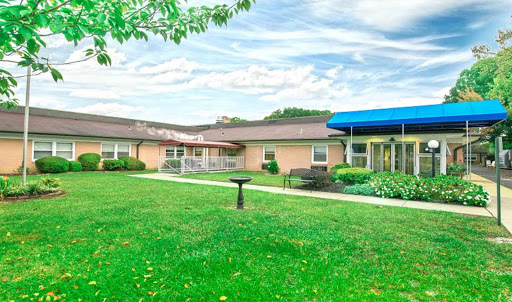 A serene view of a healthcare facility surrounded by green grass and clear skies.