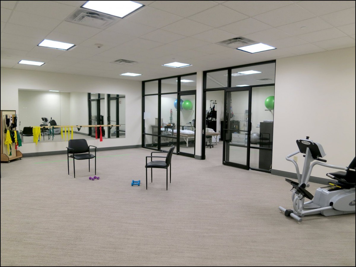 A spacious gym room with exercise equipment and chairs.