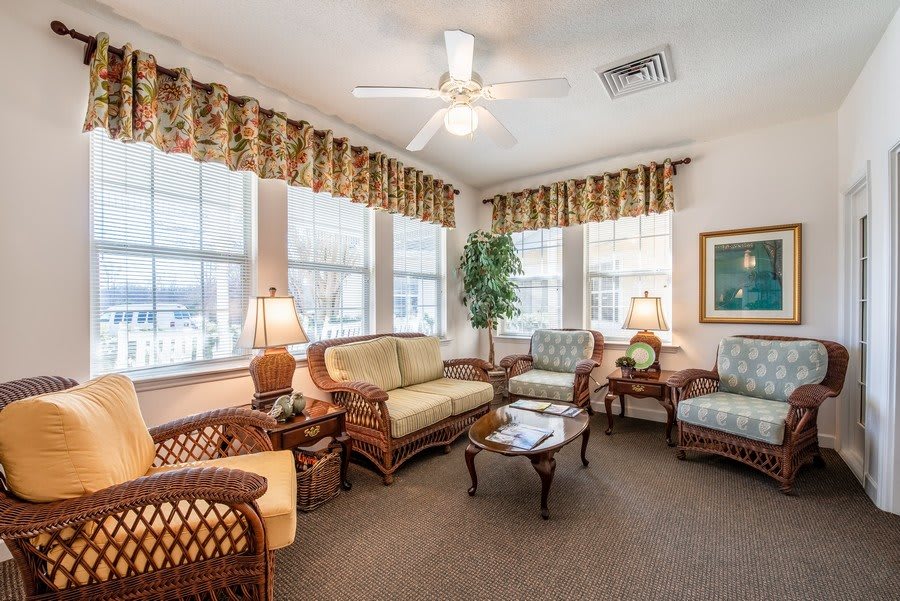 A cozy living room with wicker furniture and large windows.