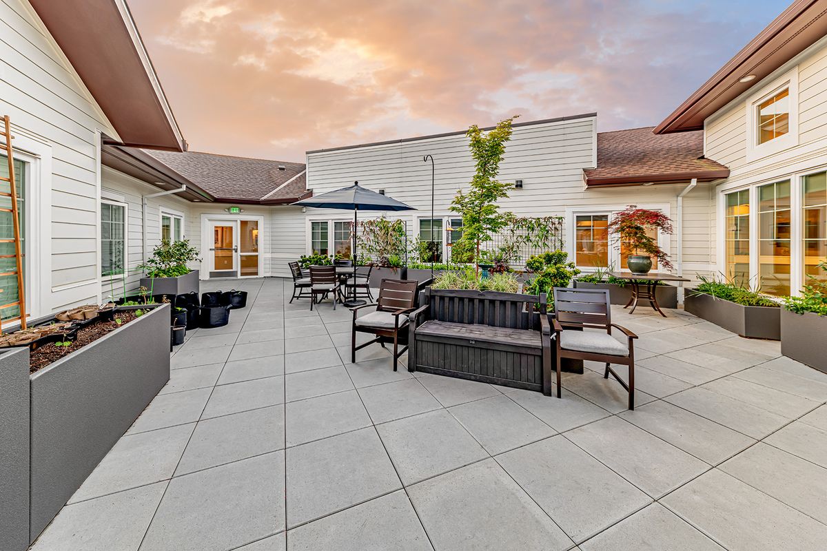 A spacious outdoor patio with comfortable seating and greenery under a sunset sky.