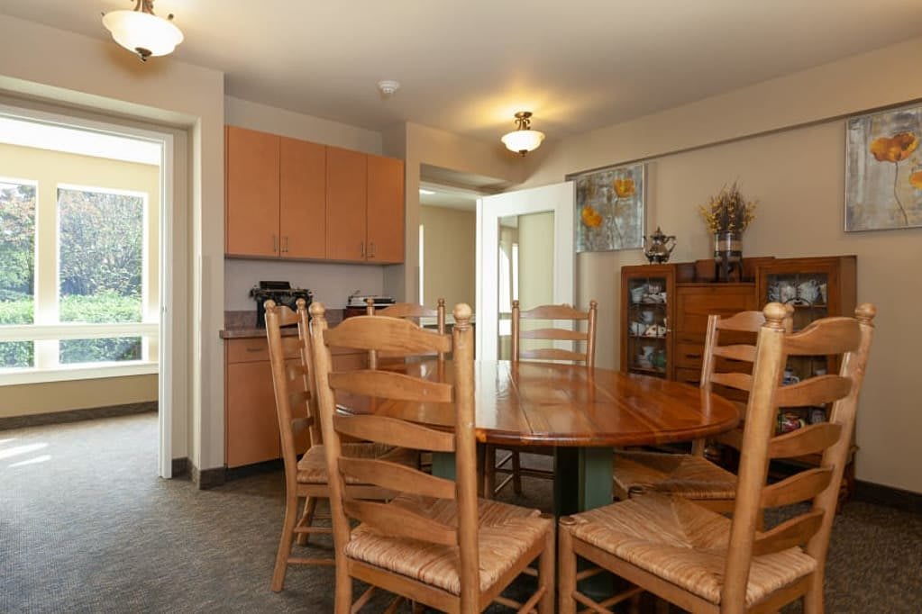 A cozy dining room with a wooden table and chairs, adjacent to a kitchen area.