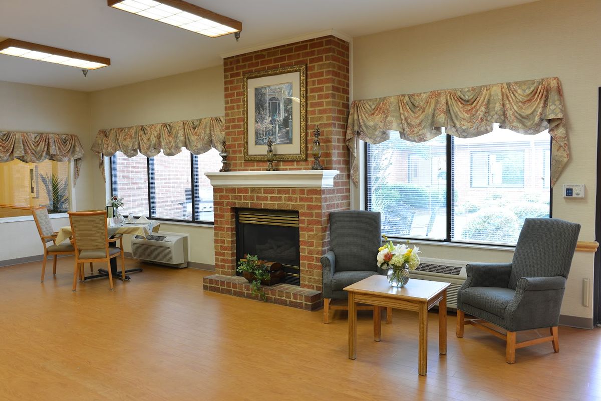 A cozy living room with a brick fireplace and large windows, featuring comfortable seating and tasteful decor.