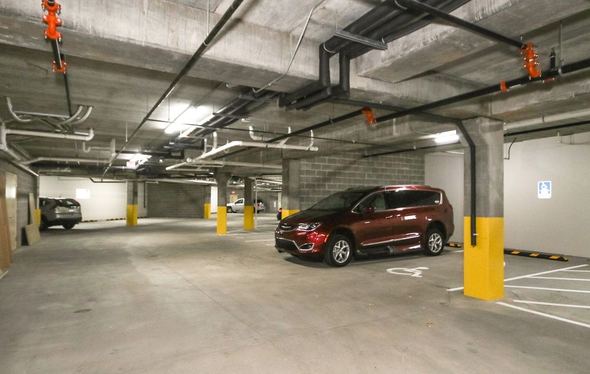 A red SUV parked in an underground parking garage with empty spaces around.