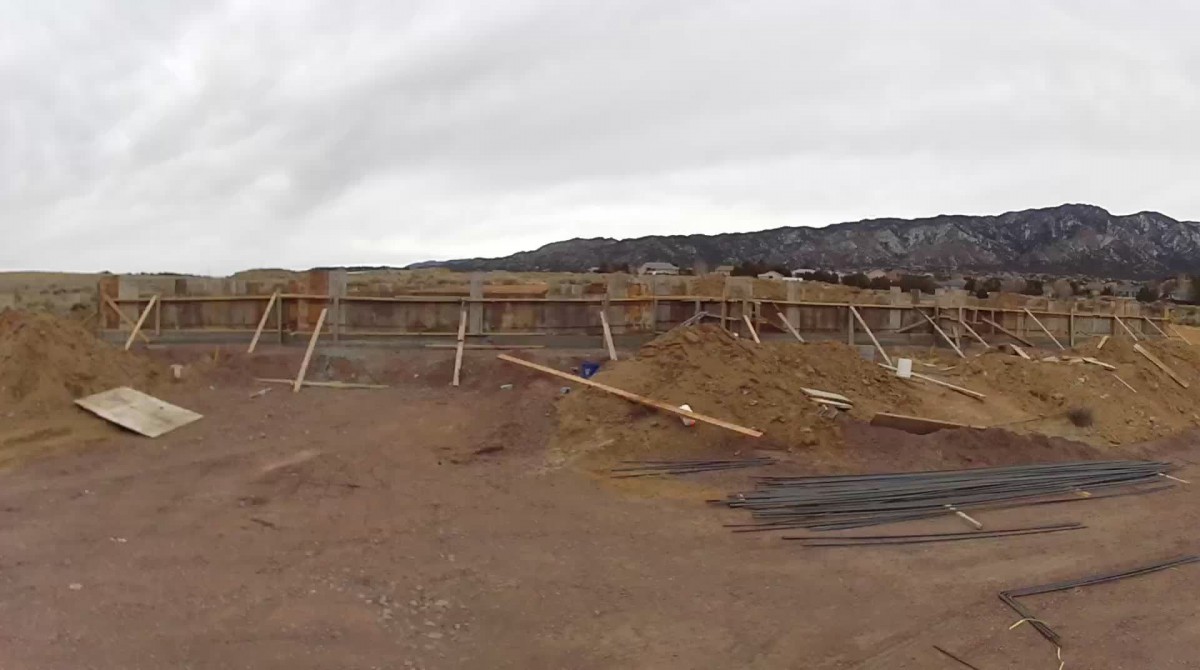 A construction site with piles of dirt and wooden structures under an overcast sky.